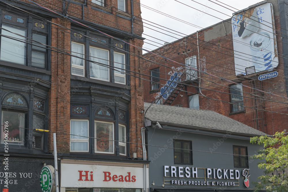 Fototapeta premium historic exterior building facade and sign of Hi Beads located at 543 Queen St W, and Fresh Picked, a produce and flower seller, located at 545 Queen St W (near Augusta Av), Toronto