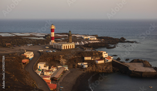 Konstfotografi Vista aérea lejana de los faros de Fuencaliente, las salinas, la pequeña cala de arena negra y el caserío de pescadores al atardecer en La Palma