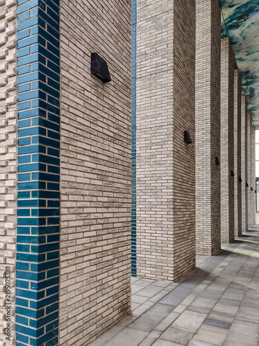 Massive brick columns of modern high-rise building. Columns are clad in light textured brick with vertical accent inserts of glazed brick. Close-up