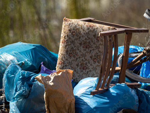 Принти на полотні Discarded Old Wooden Chair and Blue Garbage Bags in an Outdoor Waste Pile