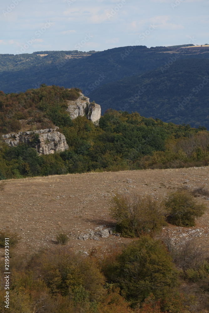 Fototapeta premium Vertical landscape of rocky cliffs and rolling green hills
