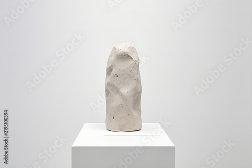 Solitary sculpture on a minimalist pedestal in a pristine white gallery
