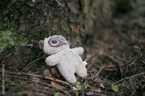 Konstfotografi Small abandoned stuffed toy lies on the cold damp forest floor beside a tree