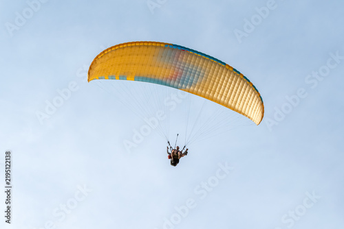 Quadro su tela Tandem paraglider with yellow and blue wing flying in the clear sky