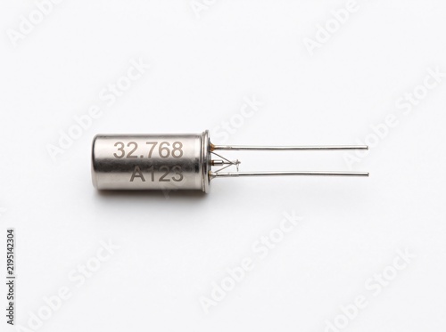 Cylindrical quartz crystal resonator on white background for precise timekeeping electronics.