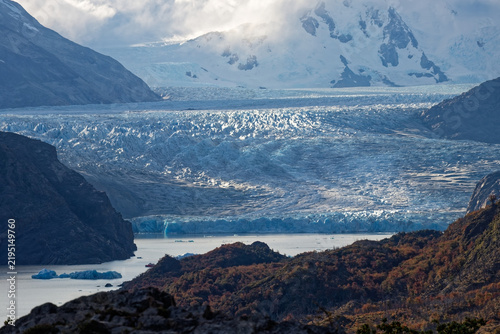 Panoramic viewpoint overlooking massive blue ice field of Grey Glacier with mountain peaks and Lago Grey sign in Chilean Patagonia.