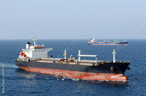 Dry-cargo ship and tanker for transporting oil floats into the sea. Rendezvous of two ships on the high seas. Strait of Hormuz. Tanker ship on the horizon