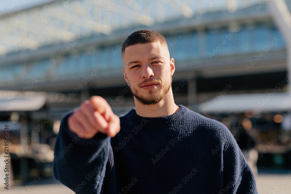 Fototapeta premium Young man pointing at camera portrait in urban street for recruitment call to action banner and marketing background