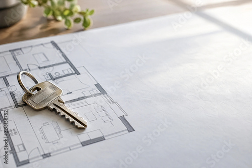Front door key lying on an architectural floor plan drawing in soft window light