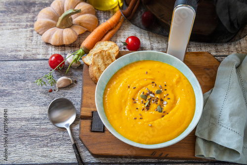 Homemade pumpkin vegetarian soup in kitchen gadget modern air fryer on wooden background. Top view flat lay background. Copy space.