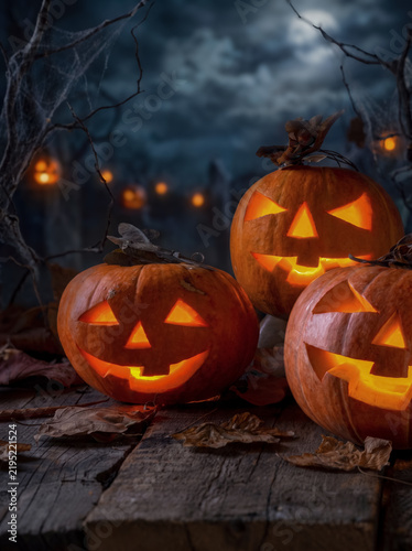 Glowing Halloween pumpkins in dark forest at night