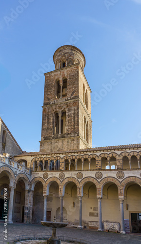 Ancient Romanesque bell tower of Salerno Cathedral in Italy. Scenic view of the historic medieval campanile bell tower rising above the atrium courtyard arches at Duomo di San Matteo in Salerno