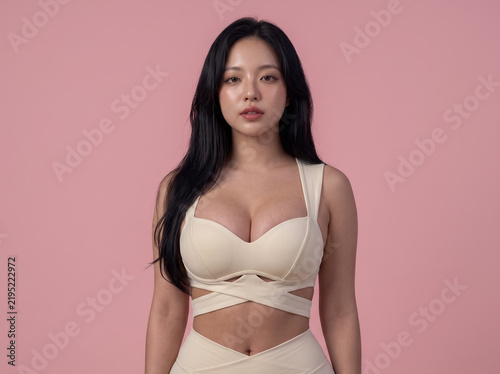 Woman in beige outfit posing on pink background