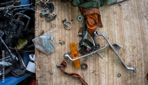 Rusty spare parts, wrenches and bolts scattered on old wooden workbench, top view