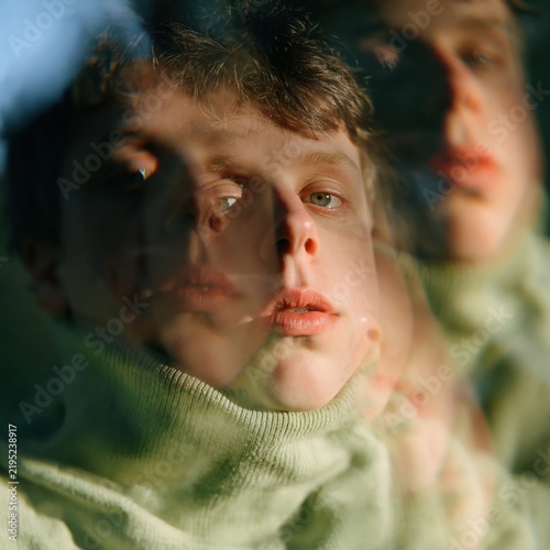 Multiple exposure closeup portrait of a young man in a green sweater for moody surreal background and poster design
