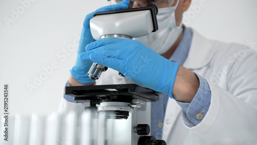 Canvastavla Scientist looking through a microscope in a bright laboratory, performing medica