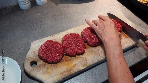 Stockholm, Sweden A cook in a residential kitchen uses a knife to etch lines into hamburger patties before frying. 