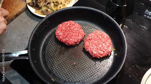 Stockholm, Sweden A cook in a residential kitchen fries homemade hamburger patties in a frying pan. 