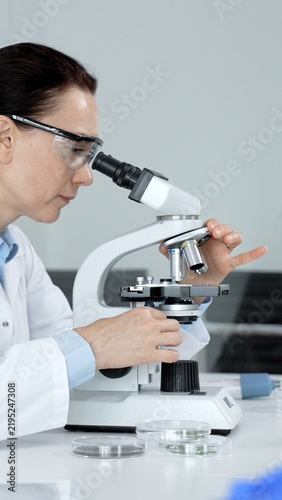 Fotografie Female scientist looking into a microscope