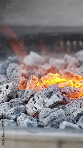 Burning charcoal briquettes glowing with intense orange flames in a backyard barbecue grill