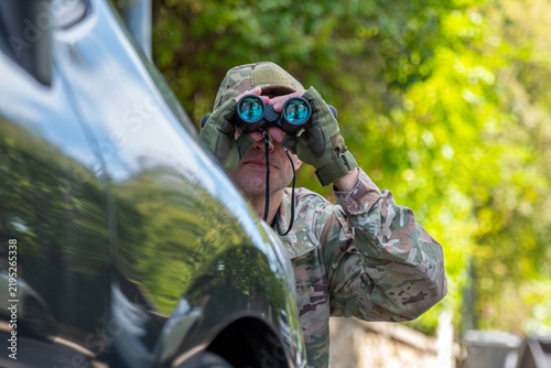 Fotografie Operative secretly watches a target near a car and gathers intelligence information during a covert mission