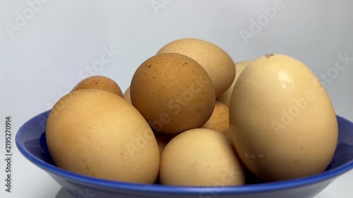 Brown and cream organic eggs stacked inside a glossy blue bowl with soft lighting and smooth textures. Perfect for healthy cooking or breakfast blog posts.