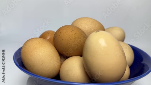 Brown and cream organic eggs stacked inside a glossy blue bowl with soft lighting and smooth textures. Perfect for healthy cooking or breakfast blog posts.