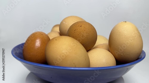 Brown and cream organic eggs stacked inside a glossy blue bowl with soft lighting and smooth textures. Perfect for healthy cooking or breakfast blog posts.