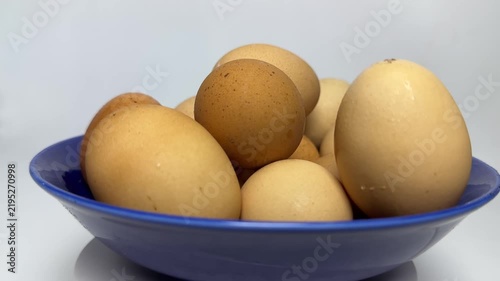 Brown and cream organic eggs stacked inside a glossy blue bowl with soft lighting and smooth textures. Perfect for healthy cooking or breakfast blog posts.