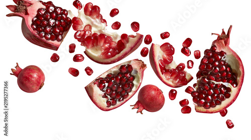 Isolated fresh pomegranate fruit with scattered red arils, whole, and various cut pieces