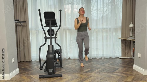 Woman runs in place with small jumps and bent arms in rhythmic motion. Home interval cardio improving endurance, coordination and fitness level.