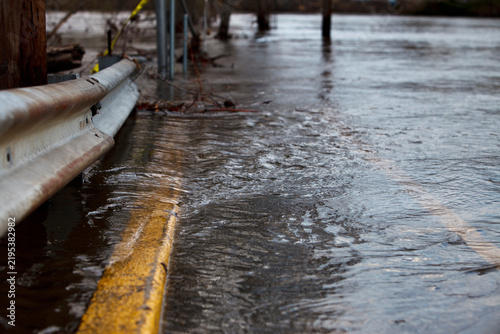 Flooded Road and Guardrail with Rushing Water Close Up Backdrop