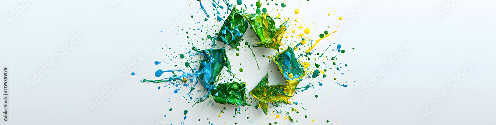 Obraz premium Symbol of recycling adorned with paint splatters on a white backdrop, emphasizing eco-friendly art and promoting sustainability for Earth Day banners