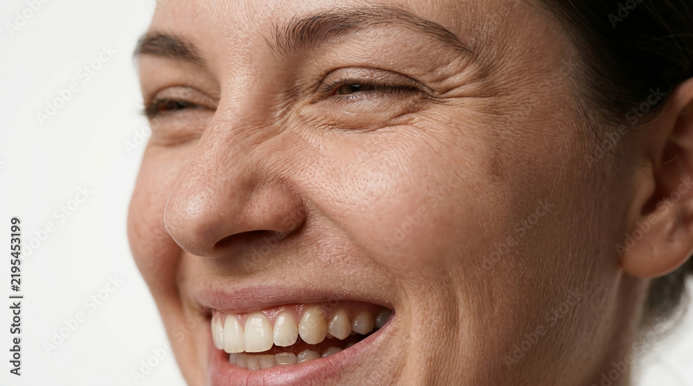 Fototapeta premium Close-up of a happy mature woman smiling showing natural skin texture, eye wrinkles, and healthy smile