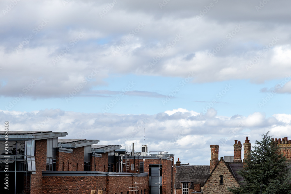 Fototapeta premium Modern and historic brick buildings contrast beneath a dramatic cloudy sky in York, England, highlighting a blend of contemporary and traditional urban architecture