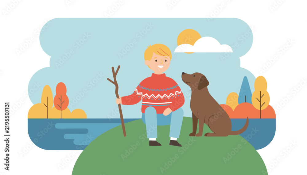 Fototapeta premium Young boy holding a wooden stick sits on a grassy hill with his loyal brown dog in a scenic autumn landscape.