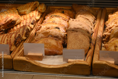 assorted fresh pastries displayed in bakery showcase, assorted fresh pastries, croissants and baked goods displayed in a bakery showcase. variety of savory and sweet pastry products arranged on wooden