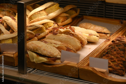 assorted fresh pastries displayed in bakery showcase, assorted fresh pastries, croissants and baked goods displayed in a bakery showcase. variety of savory and sweet pastry products arranged on wooden