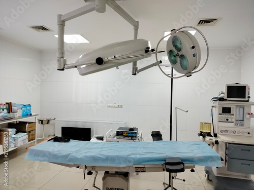 Modern hospital operating room with a surgical table, overhead surgical lamp, medical equipment, and medicines. Emergency surgical procedures, healthcare, life-saving treatment, medical care, and
