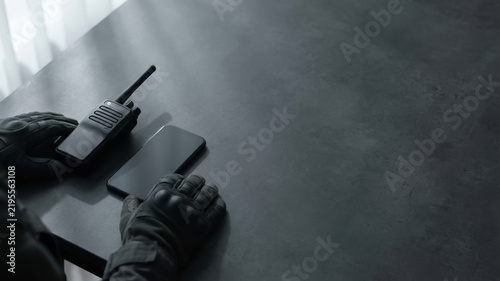 Walkie talkie security guard hand crisis management concept on dark desk with encrypted communication equipment and tense mood