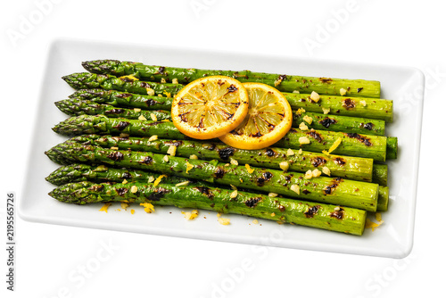 Grilled asparagus spears topped with lemon slices and seasoning on transparent background
