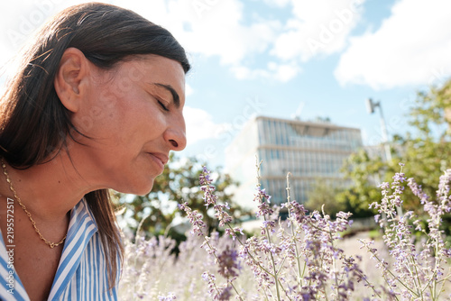 Photography Woman enjoying scent of lavender flowers in urban garden