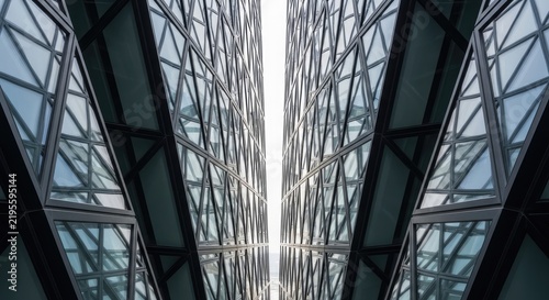 A photograph captures a striking architectural view from below, looking upwards through a complex grid of intersecting glass windows.
