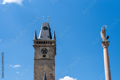 Fotografie Old Town Hall tower with Prague Astronomical Clock and Marian Column rising against a vivid blue sky in Old Town Square, Prague, Czech Republic