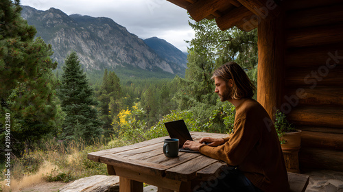 Man Working on Laptop Outdoors at Cabin Porch with Mountain View