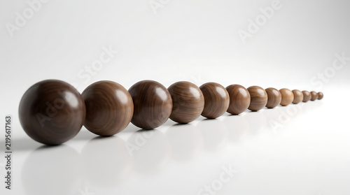 A line of wooden spheres diminishing in size on a white surface