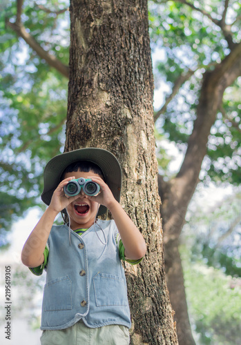 Vertical image of curious young boy with binoculars explores the wonders of nature