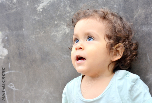 Фотография Hispanic toddler looking up with opened mouth.