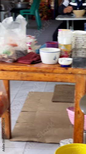 Vendor blanching egg noodles in hot soup pot and tossing in green bowl