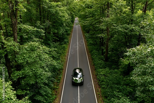 Electric car driving through green forest road